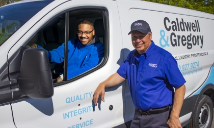 Two Caldwell & Gregory employees posing for a photo with a service van. One's in the van the other's right outside