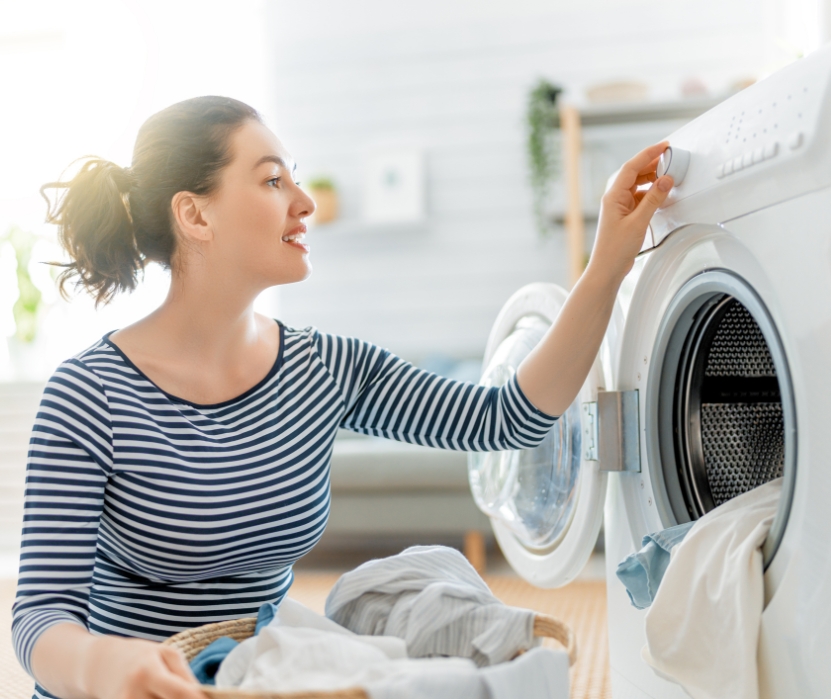 Woman putting clothes in a washer and sets the time