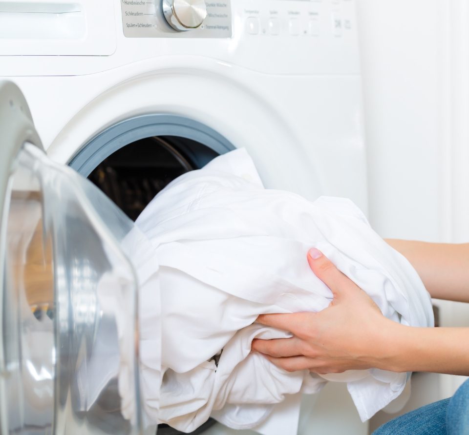 Hands taking white sheets out of a dryer