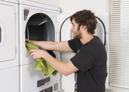 Man with a beard putting clothes in a washing machine