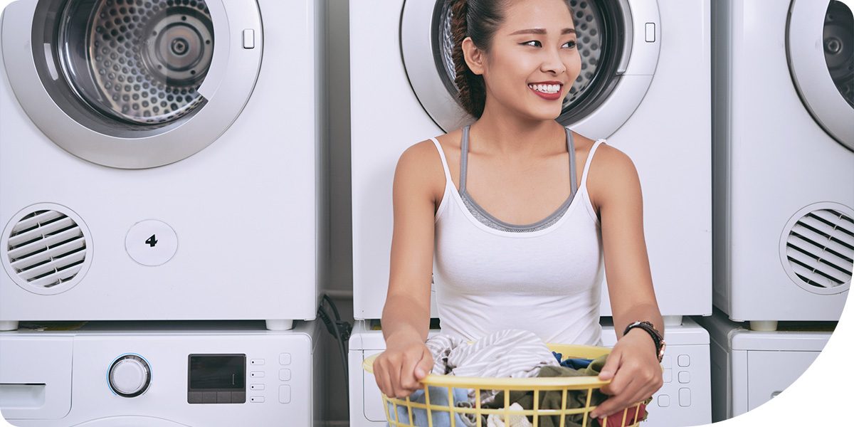 Hero image for blog post. College woman holding a laundry basket and smiling