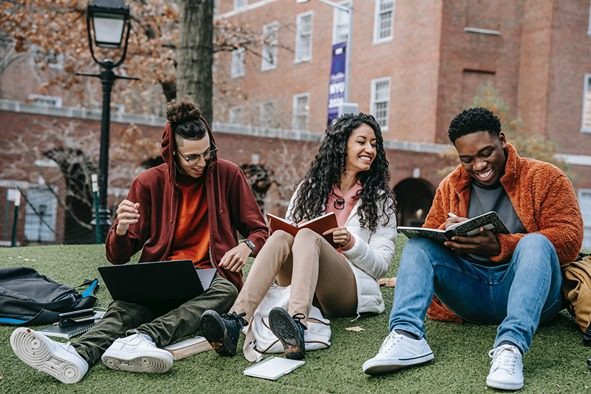 College students sitting outside studying for classes in a 3-person group