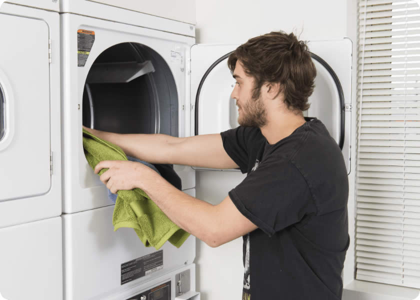 Man with a beard taking a towel out of a washing machine